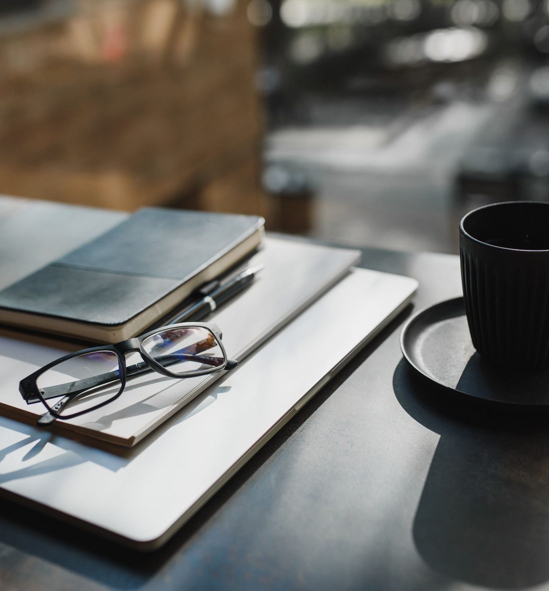 Notebooks, reading glasses and coffee on a desk